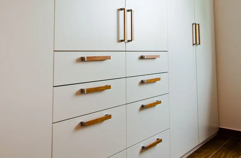 Weiße Schrankwand mit Schubladen und Holzgriffen