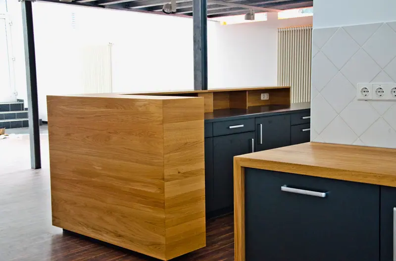 Theke mit Eichenverkleidung und dunkler Arbeitsplatte in einem Büro